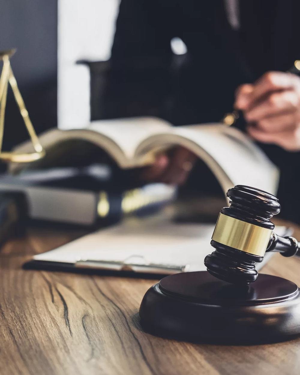 Balança da justiça, martelo e livros de direito sobre a mesa de um escritório de advocacia