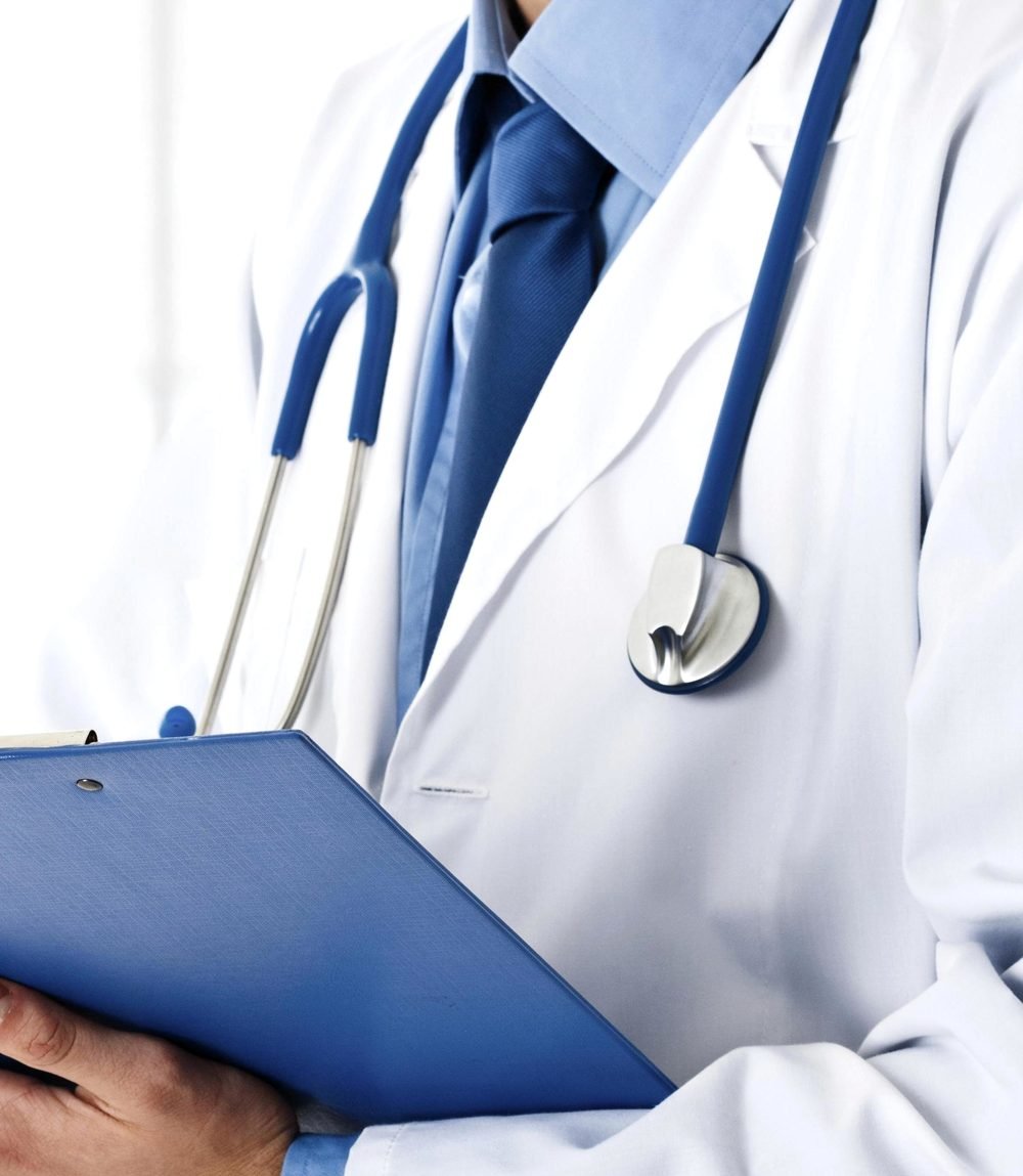 Médico de jaleco anotando em prancheta durante atendimento